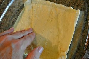 Crescent rolls, cream cheese, three types of cheese, butter, and an egg is what is in this delicious dish.